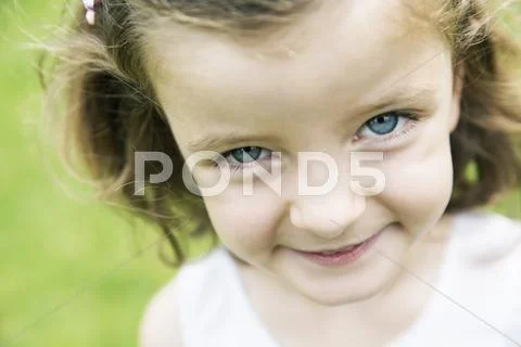 Smiling little girl with blue eyes watching at camera Stock Photos