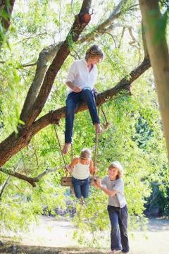 Smiling little siblings playing in tree swing Stock Photos