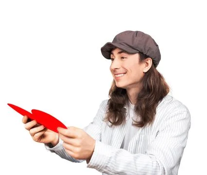 Smiling long-haired man in a cap holding a red paper heart. Happy romantic .. Stock Photos