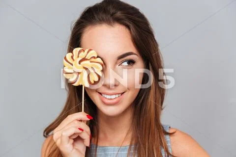 Smiling lovely young woman covered her eye with colorful lollipop Stock Photos