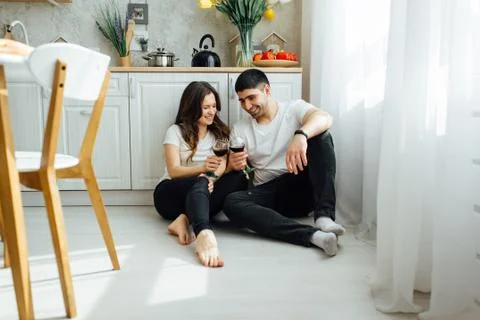 Smiling lovers drinking white wine in the kitchen Stock Photos