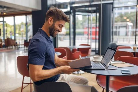 Smiling male architect is making notes during work on laptop in modern coworking Stock Photos