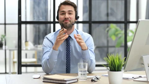 Smiling male call-center operator with headphones sitting at modern office Stock Footage 196859422