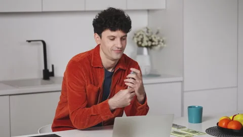 Smiling male IT developer counting cash in front of laptop, pleased with income Video stock 341015905