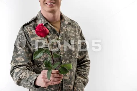 Smiling male soldier holding out rose Stock Photos