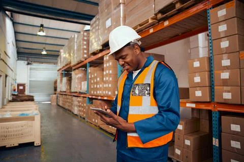 Smiling male supervisor checking stock records in digital tablet standing near Stock Photos