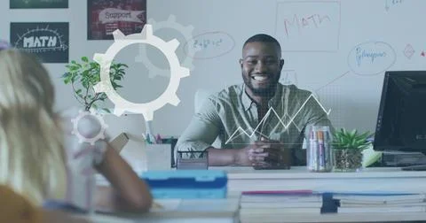 Smiling male teacher explaining math formulas at desk in classroom, with Stock Photos