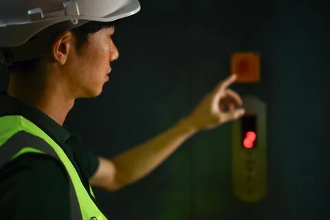 Smiling male workers pressing elevator button in warehouse. Industrial workers Foto stock