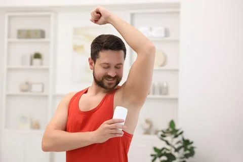 Smiling man applying solid deodorant at home Stockfoto's
