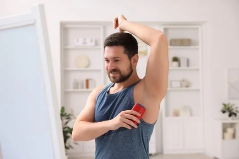 Smiling man applying solid deodorant at home Stockfoto's