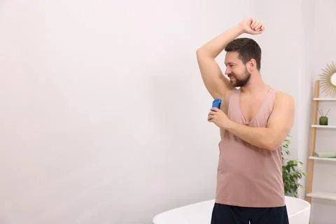 Smiling man applying solid deodorant at home. Space for text Stockfoto's
