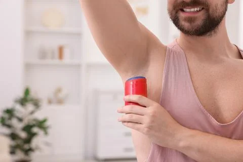 Smiling man applying solid deodorant at home, closeup. Space for text Stockfoto's
