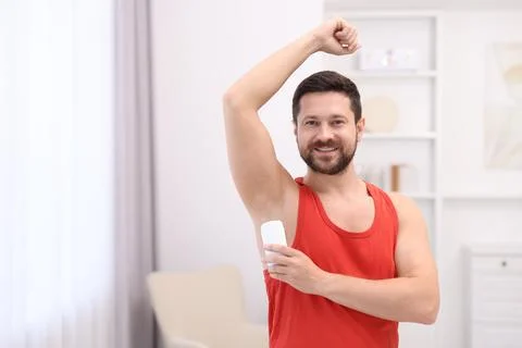 Smiling man applying solid deodorant at home. Space for text Stockfoto's