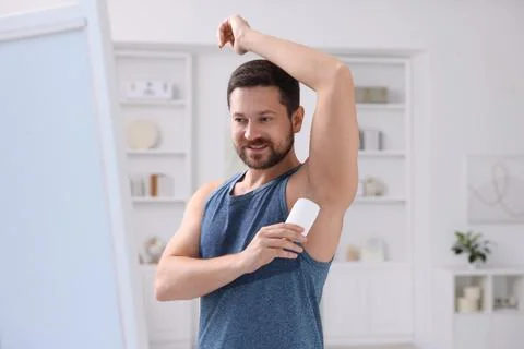 Smiling man applying solid deodorant at home Stockfoto's