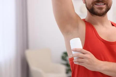 Smiling man applying solid deodorant at home, closeup. Space for text Stockfoto's