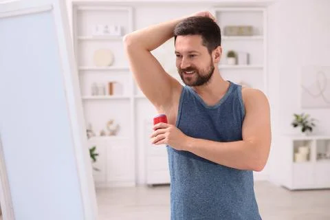 Smiling man applying solid deodorant at home Stockfoto's