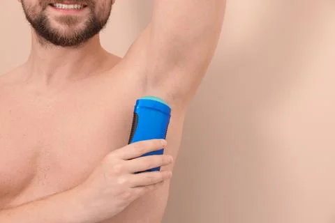 Smiling man applying solid deodorant on beige background, closeup. Space fo.. 스톡 사진
