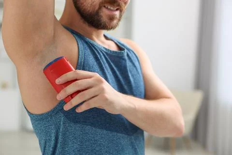 Smiling man applying solid deodorant at home, closeup 스톡 사진