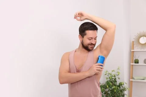 Smiling man applying solid deodorant at home. Space for text Stock Photos