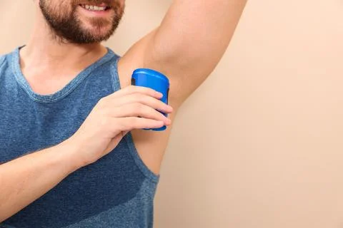 Smiling man applying solid deodorant on beige background, closeup. Space fo.. Stock Photos