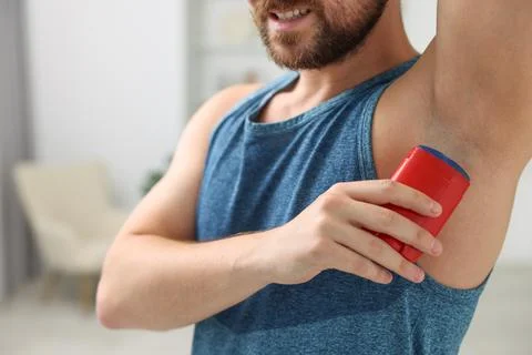 Smiling man applying solid deodorant at home, closeup Stock Photos