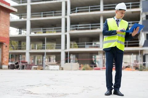 Smiling man architect in helmet working at notebook outdoors Stock Photos