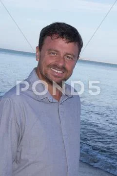 Smiling man at the beach, looking confident and casual Stock Photos