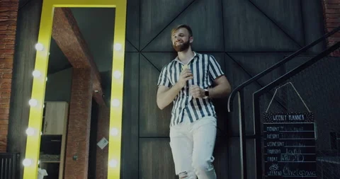 Smiling man with a beard,stylishly dressed dances near a mirror in beauty salon Video stock 139821932