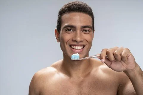 Smiling man beginning to brush his teeth Foto stock
