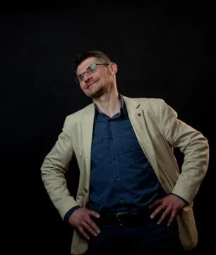 Smiling man in beige jacket and glasses bends head Stock Photos