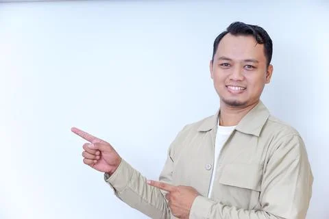 A smiling man in a beige jacket gestures with his hand, pointing at something Stock Photos