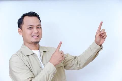 A smiling man in a beige jacket gestures with his hand, pointing at something Stock Photos