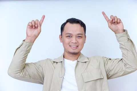 A smiling man in a beige jacket gestures with his hand upward pointing Stock Photos