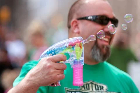 Smiling man blows bubbles with bubble gun Foto stock
