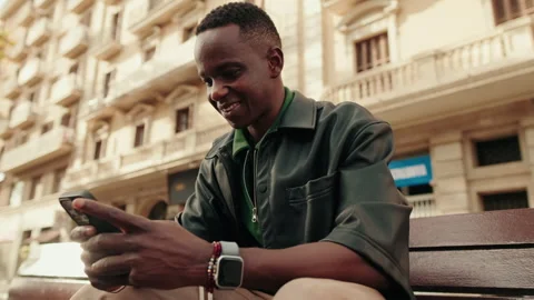 Smiling Man Browsing Phone on City Bench Stock Footage 323032064