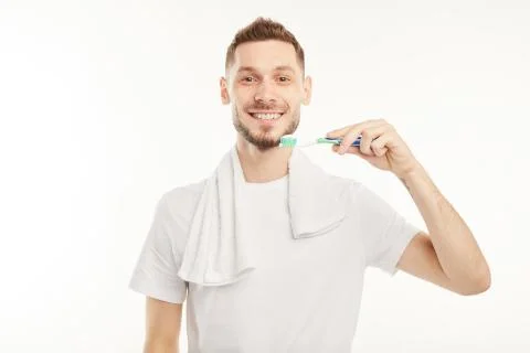 Smiling man brushing his teeth with a toothbrush on white background Stock Photos