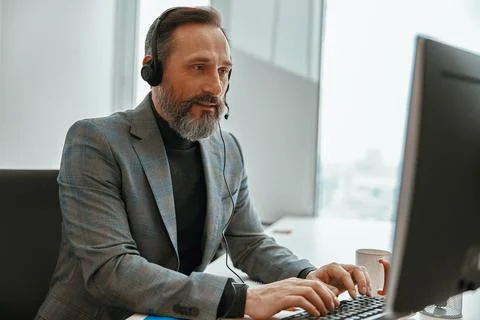 Smiling man is busy while speaking online Stock Photos