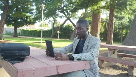 Smiling Man Chats on Tablet During Outdoor Work Session in the Park. Stock Footage 308496363