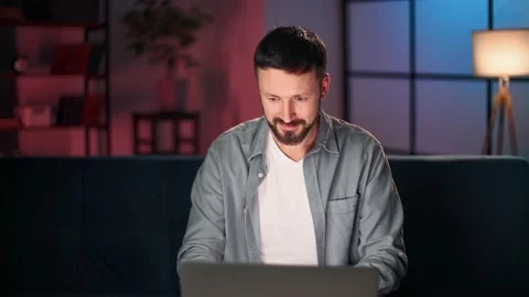 Smiling man chatting dating application browsing internet use laptop at late Stock Footage 218685267
