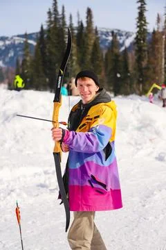 Smiling man with cold weapon in his hands, winter sport, archery Foto stock