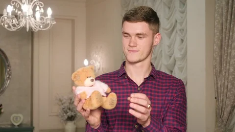 Smiling man cute playing and embracing with romantic present small teddy bear Video stock 83666275