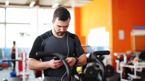 Smiling man on cycle using smart watch at the gym Stock Footage 62446448