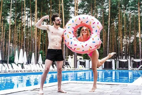 Smiling man demonstrating muscles while his girlfriend holding an inflatable Stock Photos