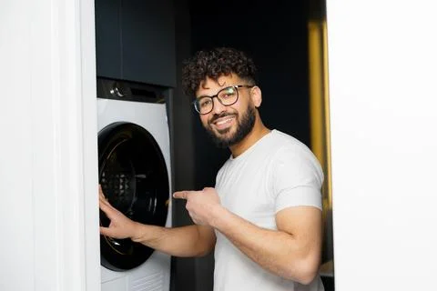 Smiling man doing laundry using washing machine Stock Photos