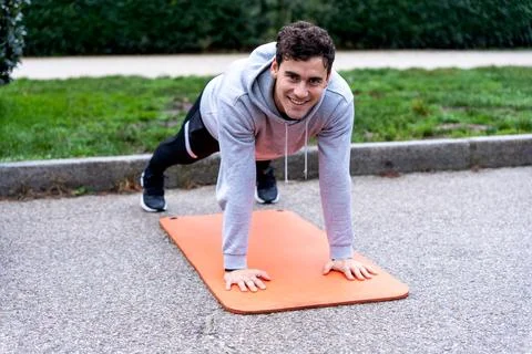 Smiling man doing plank exercise in park Stock Photos