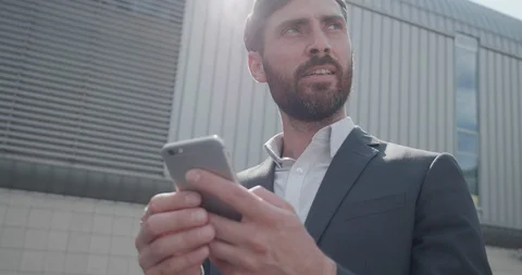 Smiling Man Dressed in grey Jacket and white Shirt Typing something on his Phone Stock Footage 125153313