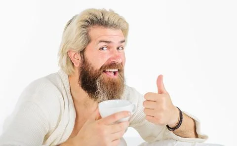 Smiling man drinking coffee in bed and showing thumb up. Breakfast in bed. .. Stock Photos