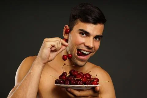 Smiling man eats red fresh cherry Stock Photos