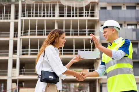 Smiling man engineer passes the keys to a young woman customer Stock Photos