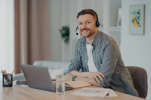 Smiling man enjoying remote work at home, looking at camera Foto stock